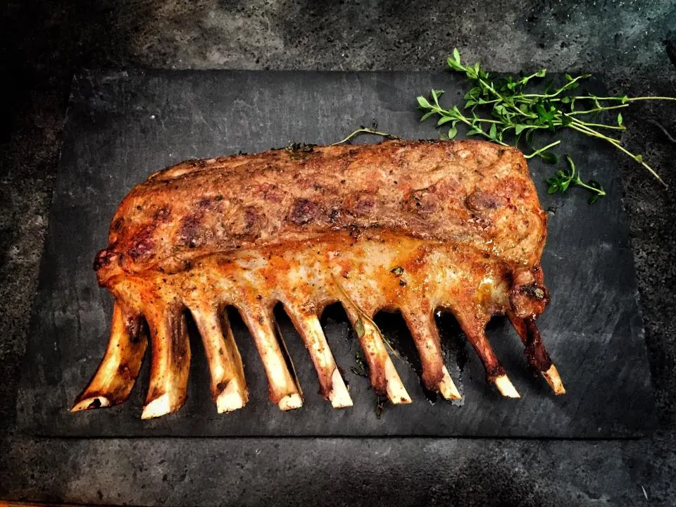 Costillar de cordero asado sobre una pizarra.