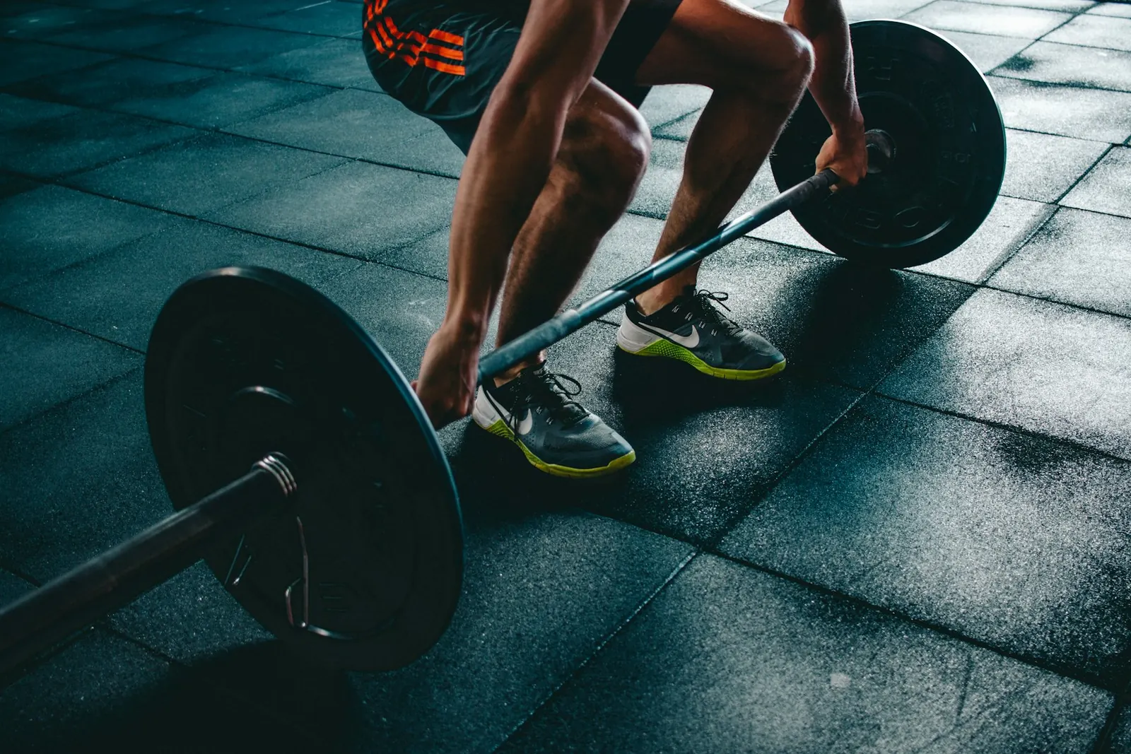 Persona levantando una barra en el gimnasio.